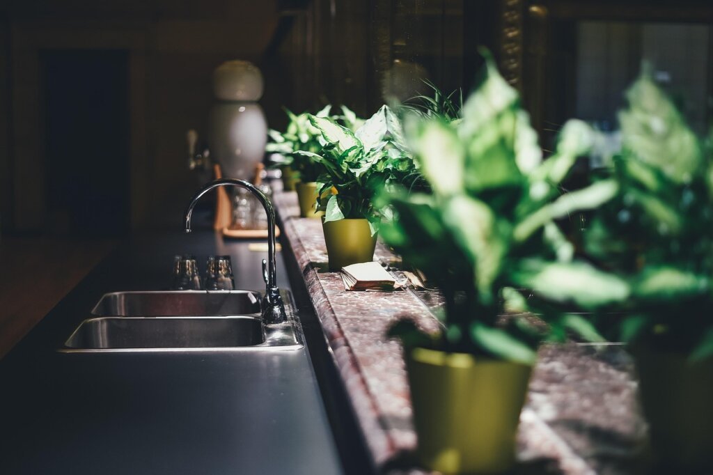 person wearing rubber gloves using a plunger on a kitchen sink