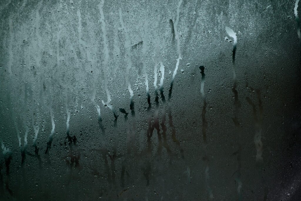 foggy window with condensation droplets in winter apartment