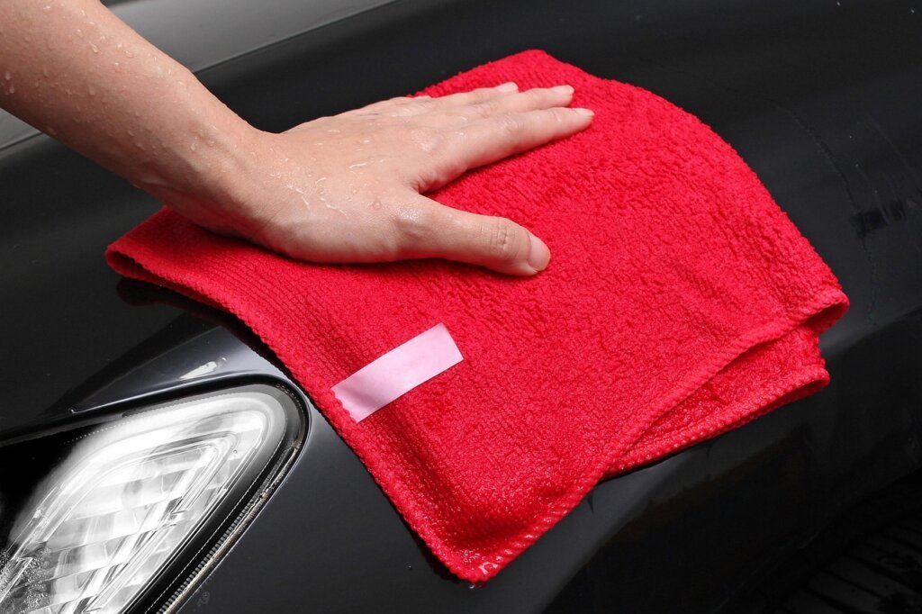 person wiping aluminum blinds with damp microfiber cloth