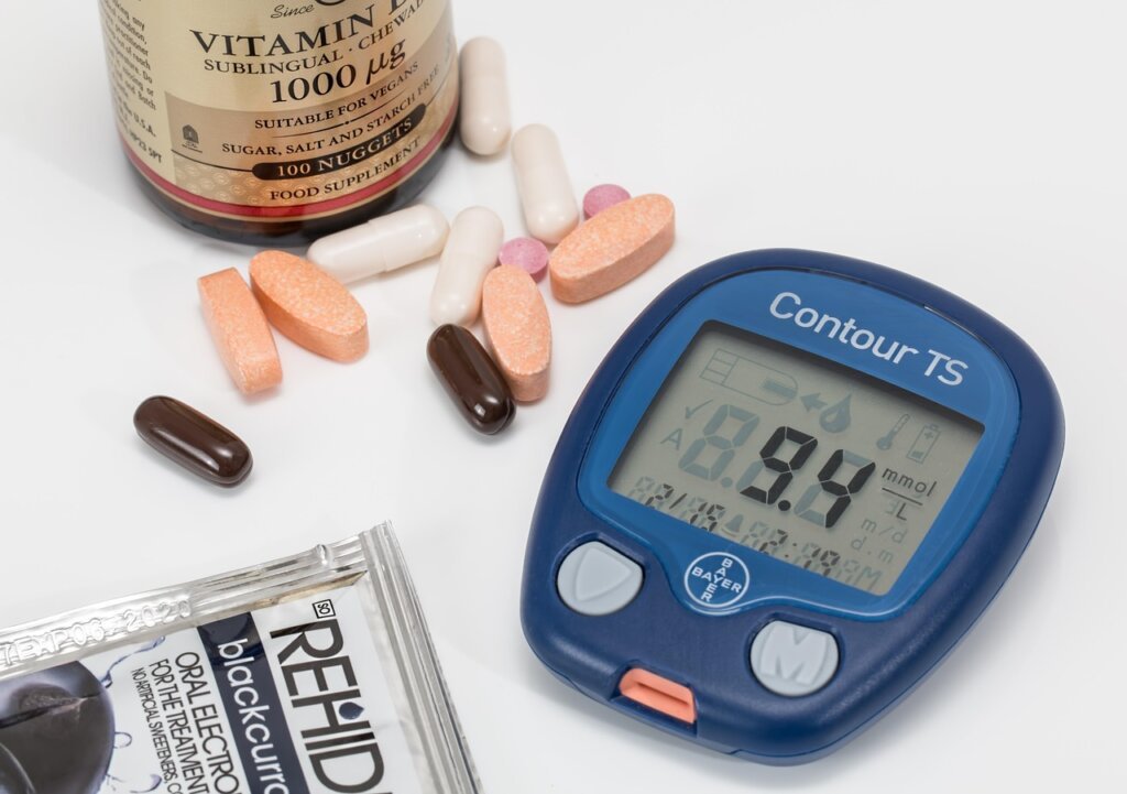 blood glucose meter and supplement bottle on desk with notebook