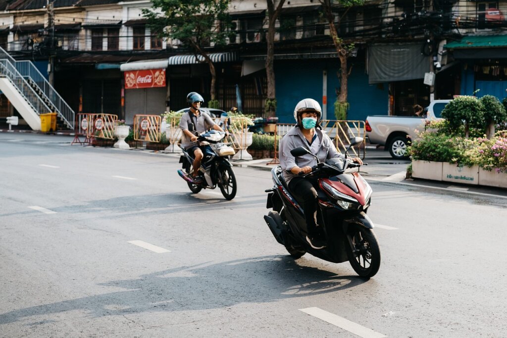 young delivery rider on motorcycle in urban street with city background
