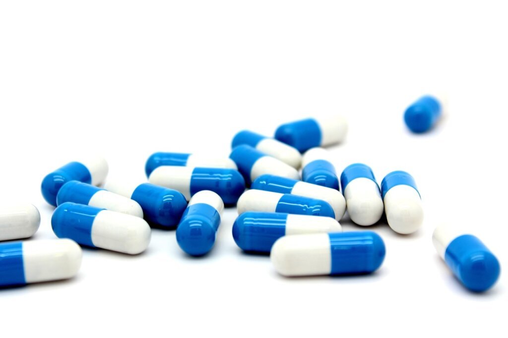 PQQ supplement capsules on white background with measuring tape
