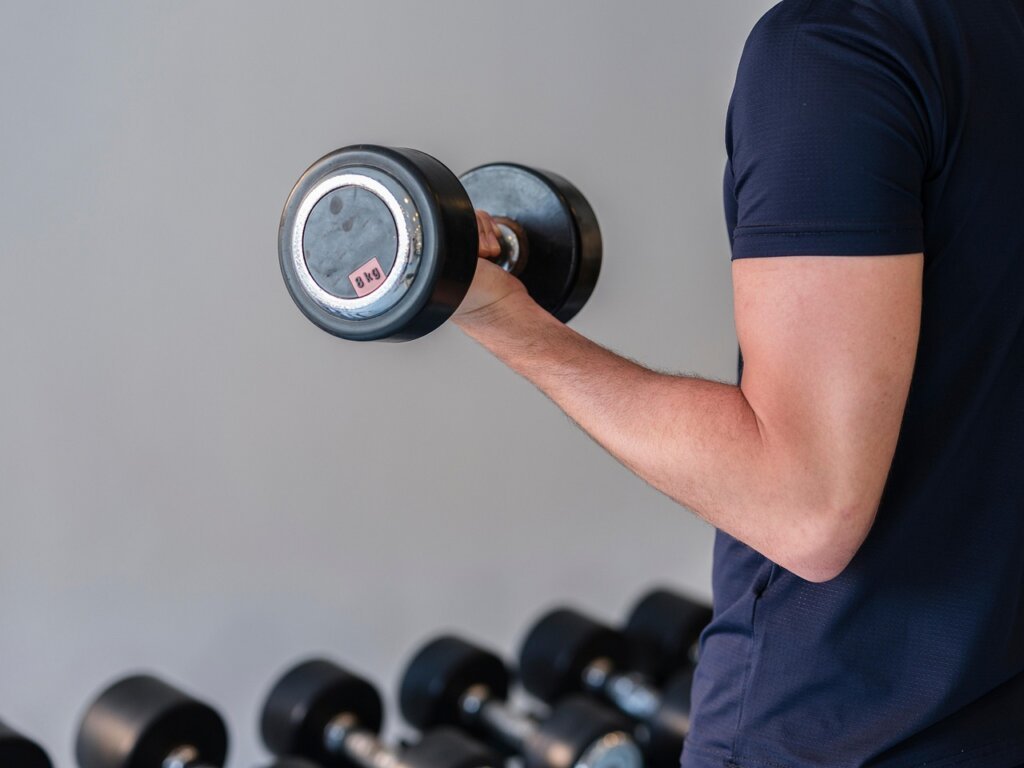 male athlete drinking protein shake after workout in gym locker room