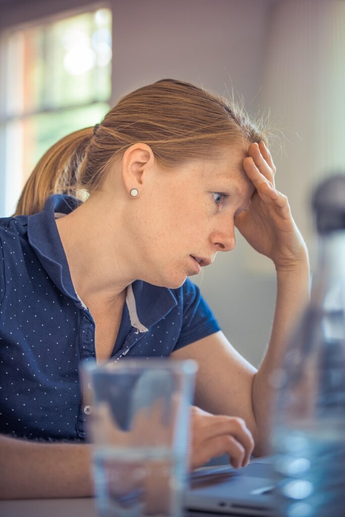 tired office worker in his late 30s resting head on desk under fluorescent light